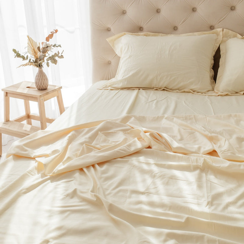 Unmade bed with cream sheets and pillows in soft morning light